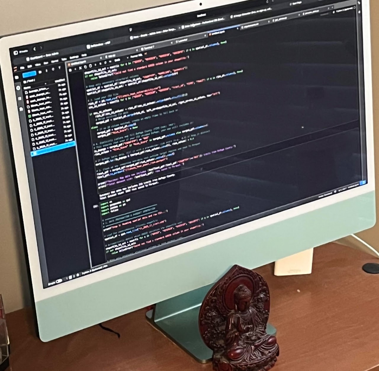 Brian's desk: an iMac showing Python and DuckDB code running next to a small Buddha statue.